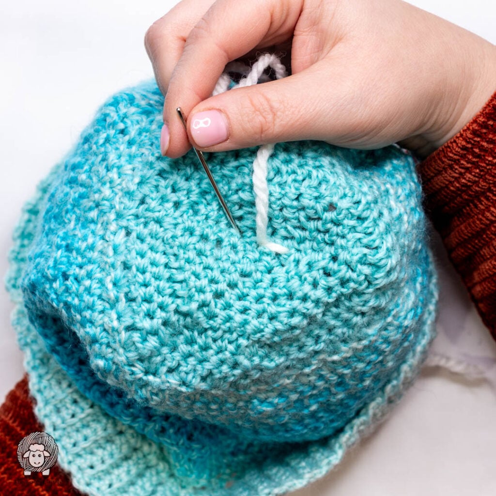 step two of how to attach a yarn pom pom to a hat