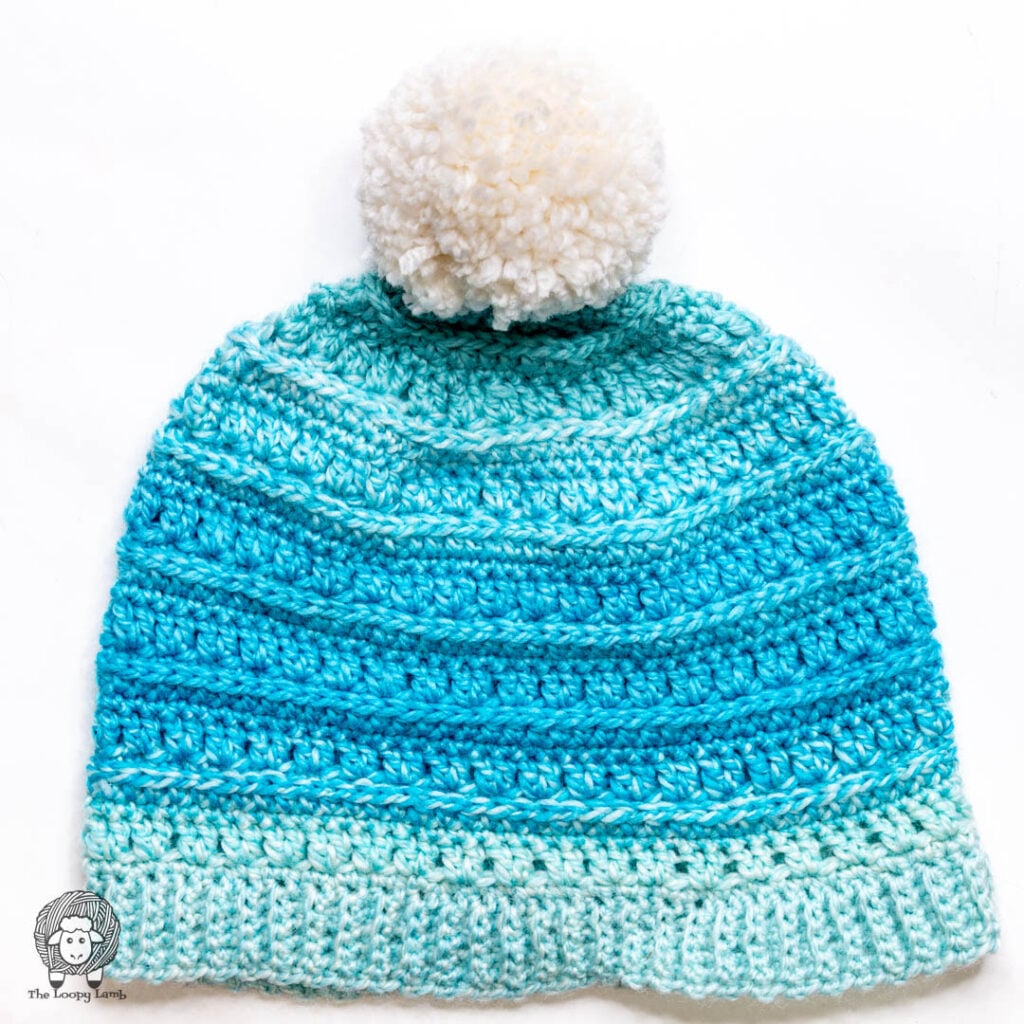 crochet hat showing a yarn pom pom that has been secured to the top