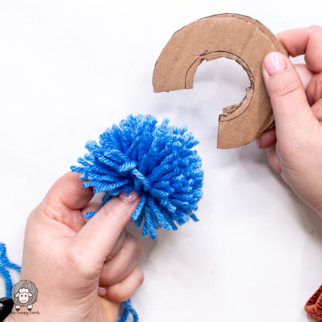 cardboard template is removed from the freshly cut pom pom