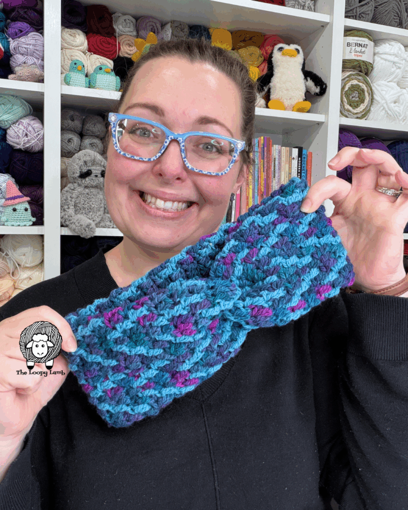 woman smiling and holding a mosaic crochet headband in front of her