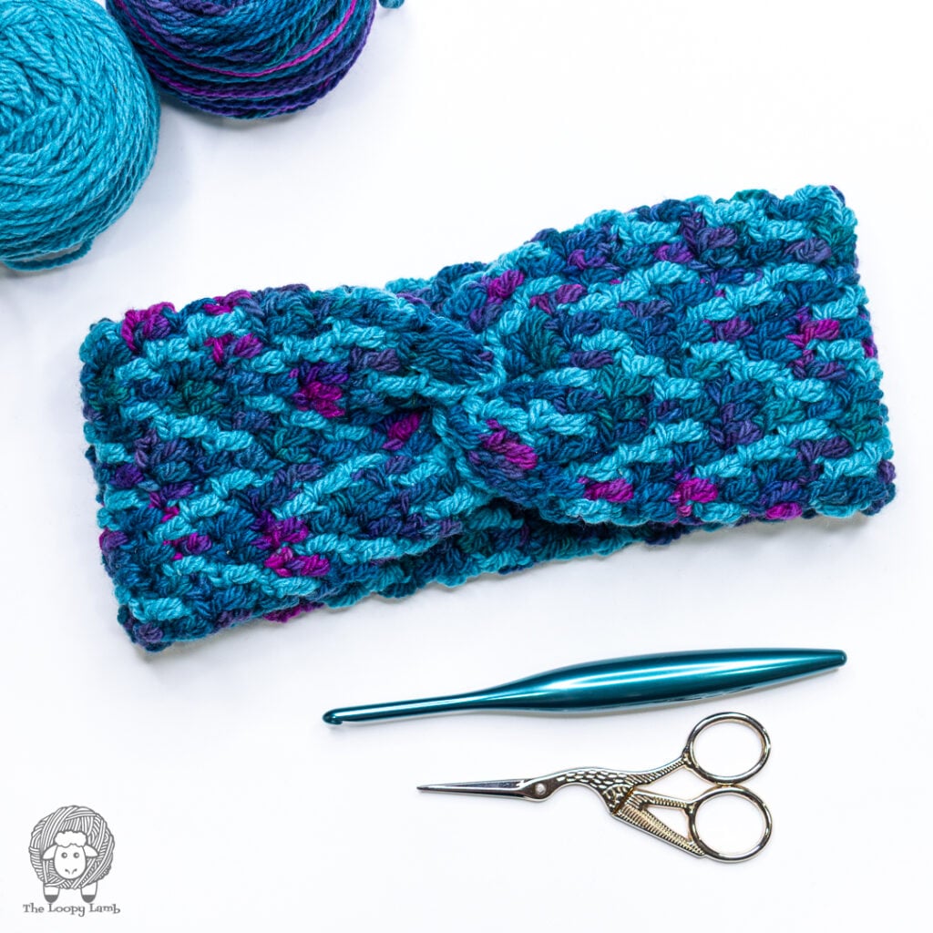overlay mosaic crochet headband on a white background next to a teal furls crochet hook and scissors