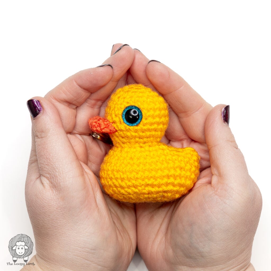 small crochet rubber duck held in a woman's palms
