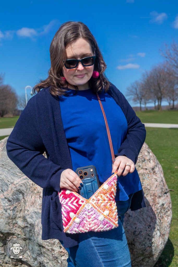 woman placing a cell phone in a small crochet granny square bag