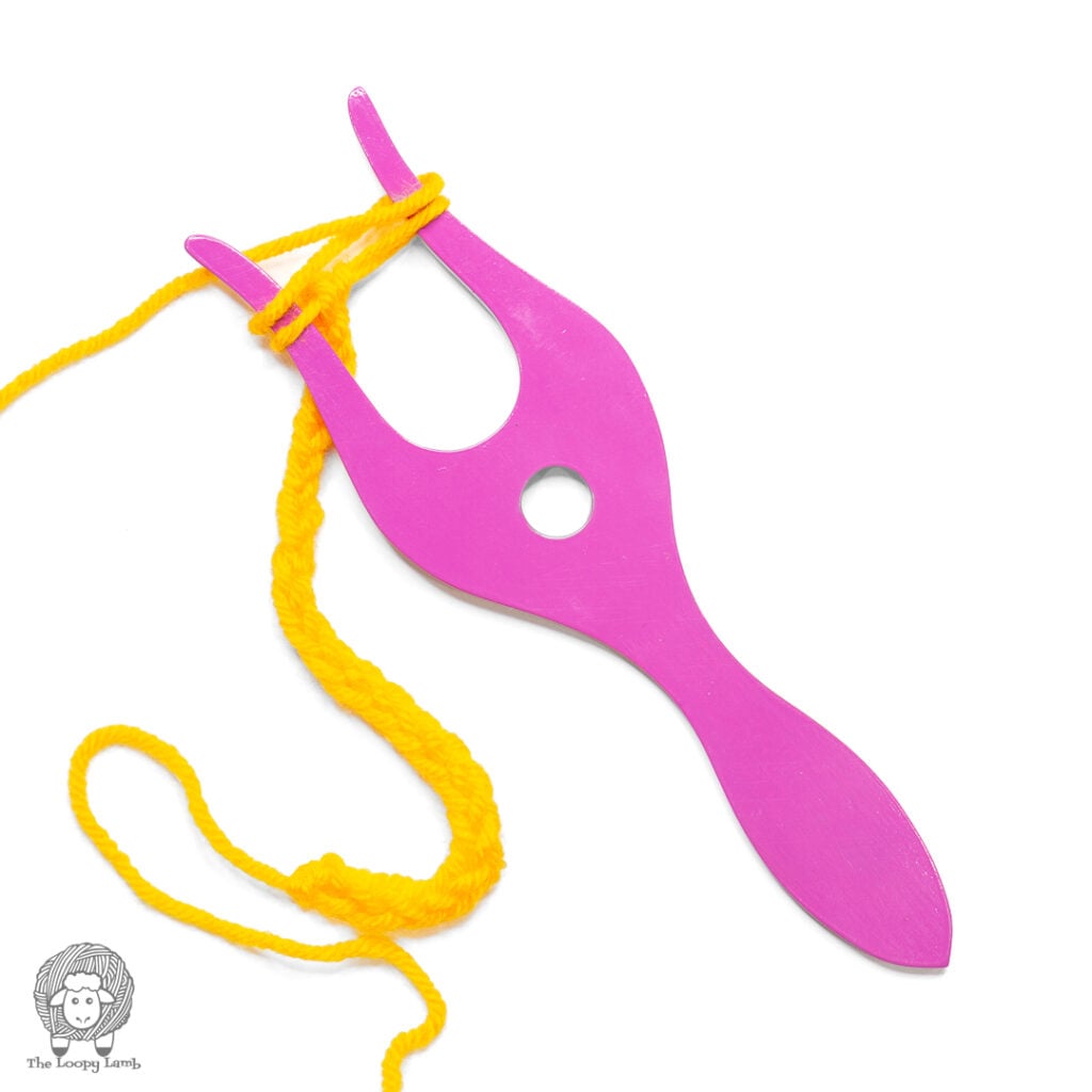 purple lucet fork on a white backgroun white a yellow i-cord in-progress