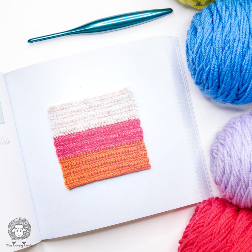 book open to show a basic crochet square next to yarn