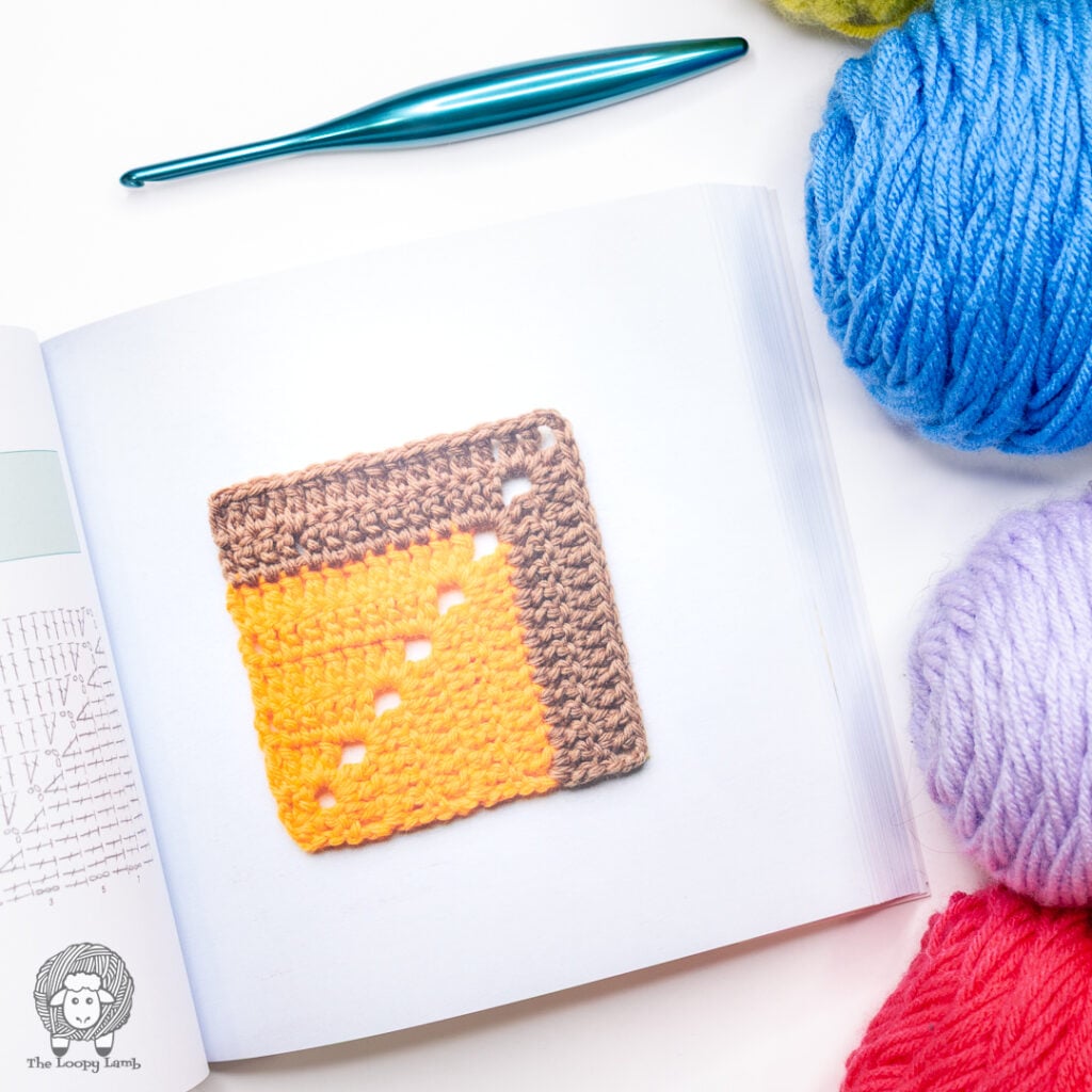 mitred crochet square from The Granny Square Bible next to yarn and a crochet hook