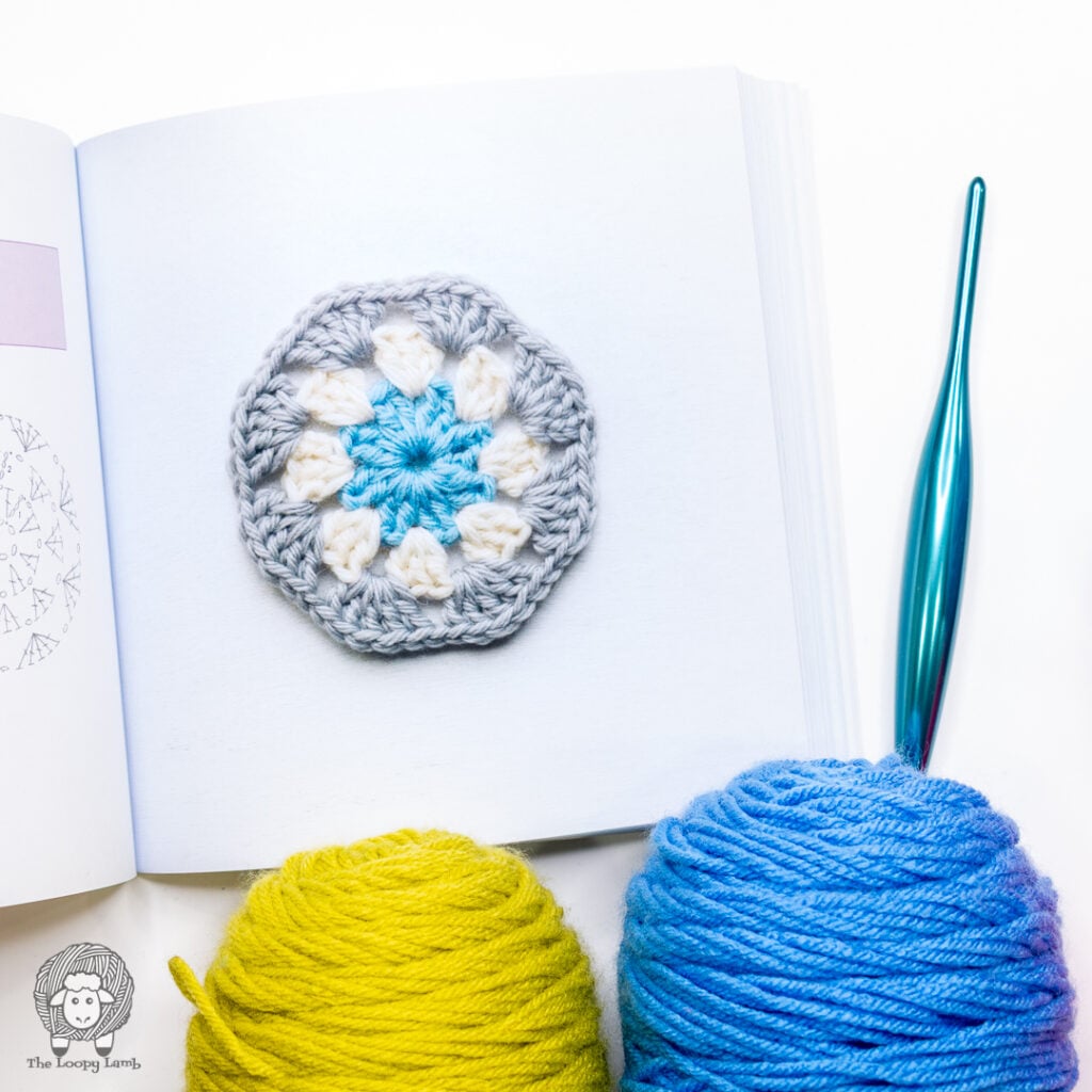 crochet hexagon motif from The Granny Square Bible next to. yarn and a Furls Crochet hook