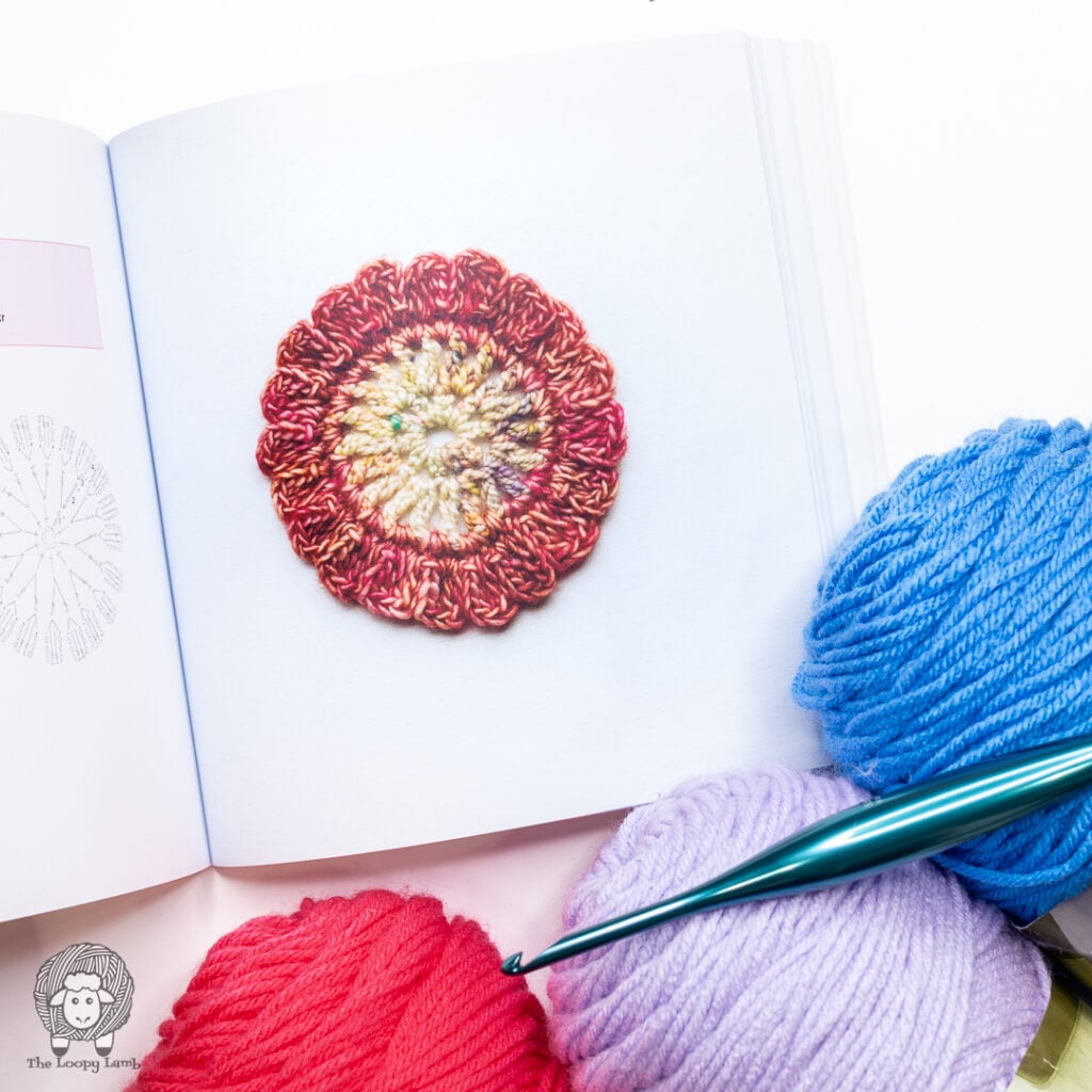 round crochet motif from The Granny Square Bible next to a crochet hook and yarn